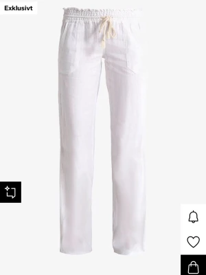 Vita Roxy linnebyxor - Snygga vita Roxy linnebyxor med rak passform och elastisk midja med dragsko. Byxorna har två fickor framtill och är tillverkade i ett lätt och luftigt linnematerial, perfekt för en avslappnad stil.