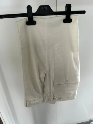 Beiga linnebyxor - Helt oanvända. Säljer ett par stilrena beiga linnebyxor i rak modell från J.lindeberg.  Perfekta för en avslappnad och trendig look. Materialet är luftigt linne som passar bra till varmare dagar. 