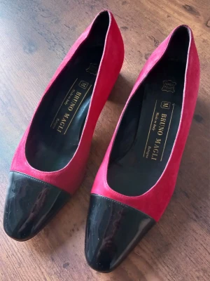 Rosa och svarta pumps från Bruno Magli Storlek 36 - Snygga pumps från Bruno Magli i rosa med svart lackad tå. Klassisk modell med rundad tå och låg klack. Tillverkade i Italien och har en lyxig känsla med kombinationen av läder och lack. Perfekta för dig som vill sticka ut med färg och stil. Storlek 36