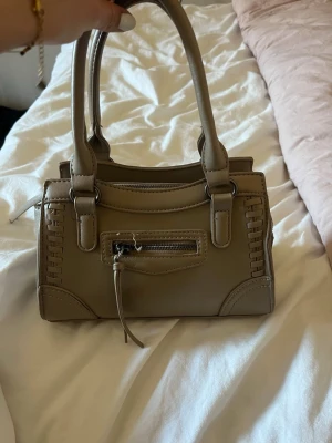 Beige handväska från Gina tricot  - Säljer denna fina handväskan eftersom att det inte riktigt är min färg på en handväska. Har använt den ungefär 6 gånger om inte mindre. Kan fås med långa band till väskan som jag inte ens rört och som är kvar i plast förpackning.