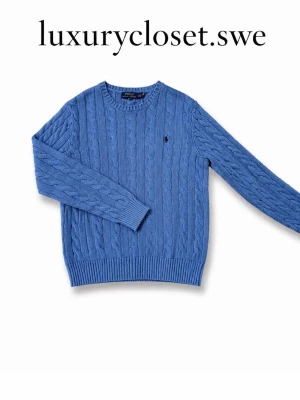 Blå kabelstickad tröja Polo Ralph Lauren - Priset kan diskuteras!!Snygg blå kabelstickad tröja från Polo Ralph Lauren med rund halsringning och diskret broderad logga på bröstet. Tröjan har långa ärmar och ribbade muddar vid ärmslut och nederkant. Perfekt för lager på lager och stilren look.