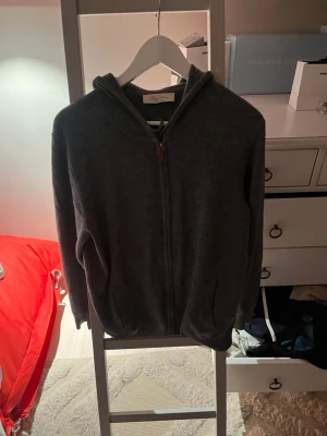 Mörkgrå hoodie med dragkedja - Tja! Mysig mörkgrå hoodie från sayless med dragkedja framtill och två fickor. Klassisk modell med huva och ribbade muddar. Perfekt för en avslappnad och stilren look. Materialet känns mjukt och bekvämt mot huden. Tröjan är i riktigt bra skick och är i Storlek s men passar m med längd 180-185. Säljer den för jag växt ut den. Skriv om ni har några frågor. Pris kan gå att diskuteras 