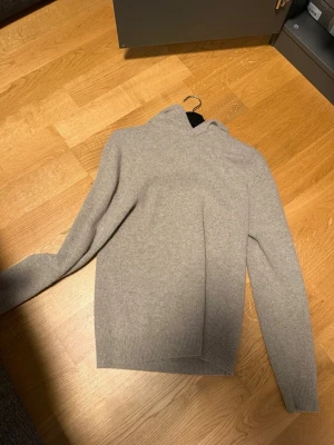 Beige hoodie i merinoull från Vailent - Knappt använd. Säljer en beige stickad hoodie från Vailent i mjuk merinoull. Tröjan har en avslappnad passform, huva och ribbade muddar vid ärmslut och nederkant. Perfekt för dig som gillar stilrena och bekväma plagg.