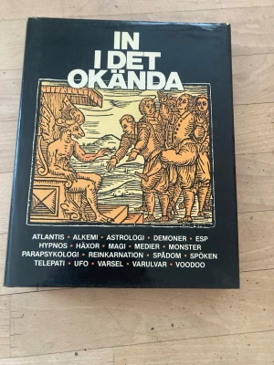 In i det okända - mystik & övernaturligt - En svart, hårdinbunden bok med titeln 'In i det okända'. Omslaget har en illustration i gult och svart med motiv av mystiska figurer. Boken tar upp ämnen som Atlantis, alkemi, astrologi, demoner, magi, spöken, UFO och varulvar. Perfekt för dig som gillar det övernaturliga.