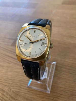 1980 Wostok Mekanisk 34mm Herrur - Säljer en urläcker guldpläterad vintage herrklocka från USSR Wostok. Mekaniskt uppvridet urverk med 18 rubiner (juveler) som fungerar fortfarande. Fortfarande i nära nyskick enligt bilder. Fungerar bra, nytt läderarmband, datumvisare, rejält mineralglas, mekanisk urverk med juveler, vattentät, osv. Säljes otestad.  Begagnat värde: 2000+ SEK Mitt pris: 789 SEK  Skickas snabbt och spårbart. Skriv vid frågor och se gärna mina andra annonser!   Mechanical watch "Vostok" of the USSR, gold-colored ca