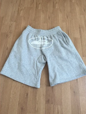 Grå sweatshorts med tryck - Grå sweatshort, säljer dem för att dem är för stora på mig dem är oanvända och helt nya. Snören finns även på shortsen bara att dem inte syns på bilden.