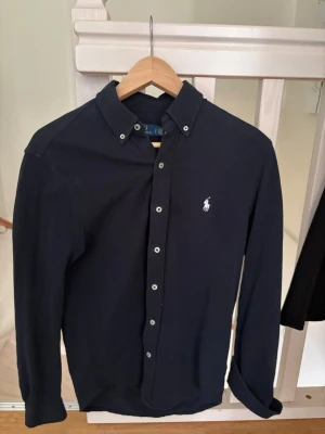 Mörkblå skjorta från Ralph Lauren - Säljer en Ralph Lauren skjorta i väldigt gott skicka med inga skador eller liknande och är använd ett fåtal gånger bara, hör av er vid frågor eller vad som helst!.