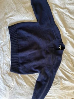 Mörkblå stickad tröja från COS i ull - V-ringad stickad tröja från Cos i 100% ull. Fint ribbad i nederkant och på muddarna. Fint skick, inte nopprig. Säljer då den tyvärr är för liten för mig