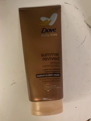 Dove Summer Revived Tanning Lotion - Dove Summer Revived Gradual Tanning Lotion med aloe vera-extrakt och återfuktande glycerin. Ger en solkysst look och lyster, anpassad för medium till mörka hudtoner. Kommer i en brun plasttub med guldiga detaljer.