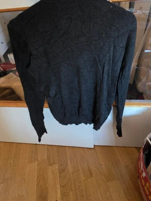 Mörkgrå basic tröja - En enkel och stilren mörkgrå tröja med rund hals och långa ärmar. Tröjan har ribbade muddar vid ärmslut och nederkant. Perfekt för lager-på-lager och passar till det mesta i garderoben.