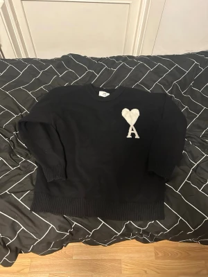 Ami Paris svart sweater med vitt hjärta – storlek S, nästan ny, mycket fint skick - Säljer en stilren och populär Ami Paris sweater i svart med det ikoniska vita hjärtat med “A” på bröstet. Tröjan är använd endast 3–4 gånger och är i mycket gott skick, nästan som ny. Ingen prislapp kvar. Detaljer  * Märke: Ami Paris * Färg: Svart med vitt hjärta/logga * Storlek: S (Small) * Skick: Använd 3–4 gånger, mycket fint skick * Passform: Normal till lite avslappnad fit beroende på kroppstyp * Material: Mjuk bomullsblandning av hög kvalitet som Ami Paris är kända för * går att diskuter.