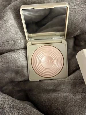 CAIA highlighter Saint Tropez - Highlighter från CAIA i nyansen Saint Tropez. Kommer i en stilren, ljusbeige dosa med spegel och har en skimrande, ljusrosa ton. Pudret har en snygg cirkelmönstrad yta och passar perfekt för att ge glow till ansiktet. Bruten förpackning men produkten är helt orörd!