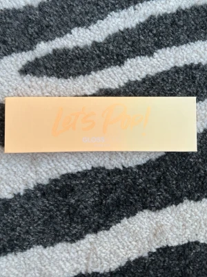 Let's Pop! ögonskuggspalett från Glossgods - Snygg ögonskuggspalett från Gloss med fem färger: brun, röd, orange, guldglittrig och rosa-glittrig. Paletten har spegel i locket och kommer i en peachfärgad förpackning. Skyddsplasten sitter kvar. Själva lådan den kom i har jag inte kvar.