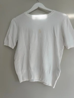 Vit kortärmad stickad t shirt ifrån Zara - Säljer denna vita kortärmade stickade t shirten i storlek M ifrån Zara. Tröjan har en liten fläck på framsidan därav priset! 