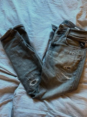 Gråa Replay jeans med slitningar  - Säljer nu dessa riktigt snygga Replay anbass jeans med slitningar 🤙storlek 31/32 skick 7/10 lite slitna på  några ställen men de är inget som syns eller känns👌skriv om du har några frågor⭐️🙏
