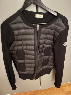 Svart cardiganjacka från Moncler - Säljer min moncler pga att den är för liten, såklart äkta. Har ett litet hål vid axeln som snabbt går att laga, därav priset.