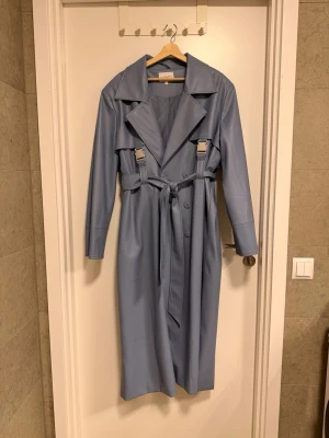Trenchcoat Angelica Blick x NA-KD - Efter många om och men är det tyvärr dags att säga adjö till min älskade trenchcoat från Angelica Blick x NA-KD. Knappt använd, men ack så snygg. Maxi trench i PU material. Skynda fynda!