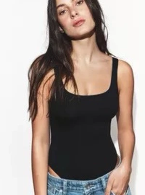 Zara body - En svart, tight linnetopp med breda axelband och rundad halsringning. Toppen är ärmlös och har en enkel, klassisk design som är lätt att matcha med olika outfits. Materialet ser ut att vara syntet och stretchigt för en bekväm passform.