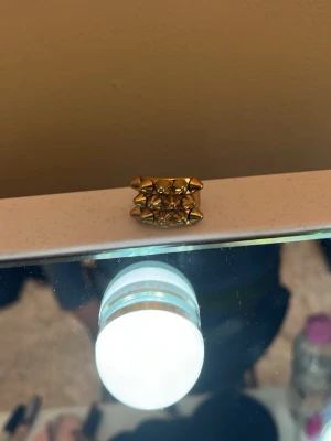 Edblad ring - Cool ring i guldfärgad metall med flera små nitar runt hela bandet. Ringen har en bred design och ger ett edgy intryck, perfekt för dig som gillar statement-smycken. Märke saknas.