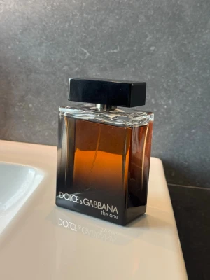 Dolce & Gabbana The One EdP 150ml - Dolce & Gabbana The One Eau de Parfum Pour Homme i en elegant rektangulär glasflaska med svart lock. Flaskan har en mörkbrun toning som ger ett lyxigt intryck och rymmer 150 ml. En klassisk och maskulin doft från ett ikoniskt märke.