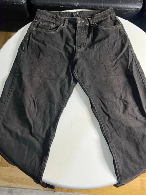 Svarta jeans från MONKI - Säljer ett par svarta jeans från MONKI med klassisk femficksmodell och raka ben. Jeansen har kontrastsömmar och normal midja. Materialet är bomull med en mjuk känsla och de passar perfekt till en avslappnad streetstil.