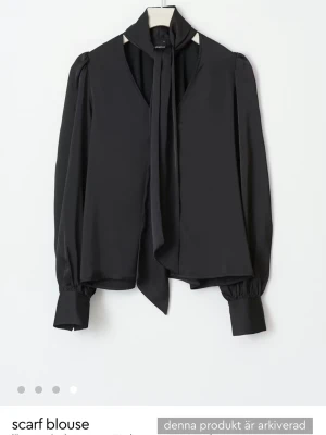 Söker!!!!!!Svart scarfblus med puffärm - Stilren svart blus med knytbar scarf i halsen och långa puffärmar. Blusen har breda manschetter med knappar och en lös, flowy passform. Perfekt för dig som gillar en chic och trendig look. Materialet ser ut att vara mjukt och lätt, troligen polyester eller viskos.