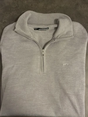 Ljusgrå halvzip från J.Lindeberg - Snygg ljusgrå stickad tröja från J.Lindeberg. Storlek S. Skriv vid frågor eller funderingar. 