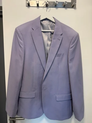 Ljuslila kavaj asos - Snygg ljuslila kavaj från Asos med klassisk passform och två fickor framtill. Kavajen har ett stilrent snitt, enkelknäppning och är helfodrad med ljusgrått innerfoder. Perfekt för dig som vill sticka ut med färg och stil.