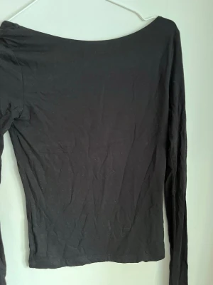 Svart långärmad topp med öppen rygg - Säljer en supersnygg svart långärmad topp med öppen rygg från Gina Tricot. Storlek S