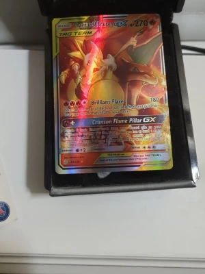 Charizard & Braixen GX Pokémonkort - Säljer ett Charizard & Braixen GX TAG TEAM Pokémonkort med holografisk yta. Kortet har färgstark design med röd, gul och orange ton samt detaljer i silver. Perfekt för samlare eller Pokémonfans som vill utöka sin samling.
