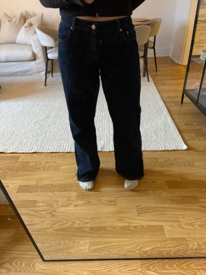 Mörkblå raka jeans från NA-KD - Säljer ett par mörkblå jeans från NA-KD med rak passform och klassisk femficksdesign. Jeansen har visst slitage längst ner.