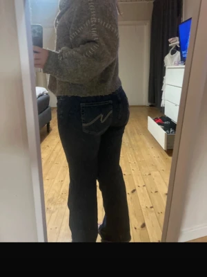 Mörkblå jeans från Nelly - Säljer ett par mörkblå jeans från Nelly med raka ben och dubbla knappar i midjan. Jeansen har klassiska fickor och en snygg detaljsöm på bakfickan. Perfekta för en avslappnad och trendig look.