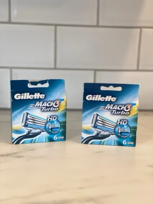 Gillette Mach3 Turbo rakblad 6-pack - Två förpackningar Gillette Mach3 Turbo rakblad, 6-pack vardera. Blå och silverfärgade förpackningar med tydlig logga och bild på rakblad. Perfekt för dig som vill ha en nära och smidig rakning.