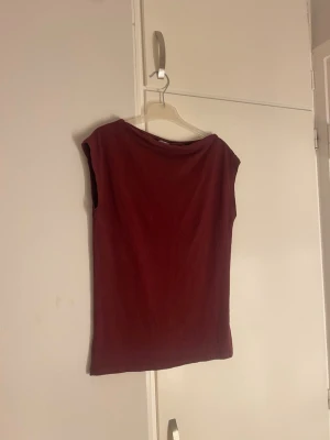 Mörkröd ärmlös topp lager 157 - En stilren mörkröd topp från lager 157 med ärmlös design och rundad halsringning. Toppen har en enkel och clean look, perfekt att matcha med jeans eller kjol. Lägger sig fint runt midjan. Nästan aldrig använd, pris går verkligen diskuteras 