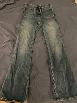 Blå bootcut jeans, Polo Ralph Lauren - Säljer ett par blå bootcut jeans från Polo Ralph Lauren med fickor på framsidan. Hög midja. Notera ett par mindre slitningshål.