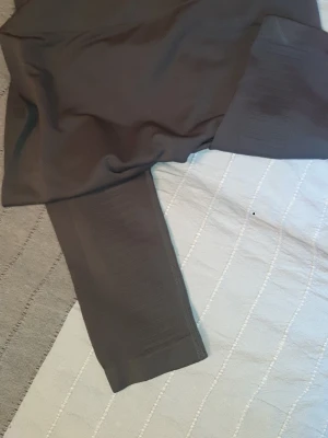 Mörkgrå sömlösa training leggings från Workout - Säljer ett par mörkgrå sömlösa leggings med hög midja och ribbade detaljer längs benen. Materialet är stretchigt och mjukt, perfekt för en bekväm och snygg look. Passar till både träning och chill. Inga synliga loggor eller märken.