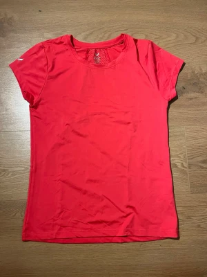 Röd sport-tshirt från SOC - Snygg röd sport-tshirt från SOC med rund halsringning och korta ärmar. Tillverkad i ett lätt och ventilerande funktionsmaterial, med meshpanel i ryggen för extra andningsförmåga. Perfekt för träning och aktivitet.