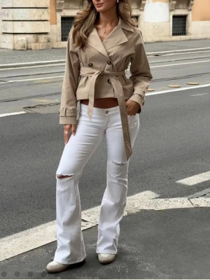 Vita bootcut jeans med slitningar - Säljer ett par vita bootcut jeans med slitningar på båda benen. De är använda max 5 gånger!                                                               Jeansen har låg midja, klassiska fickor. Materialet är stretchigt denim som sitter snyggt och bekvämt. Perfekta för en trendig och avslappnad look. 