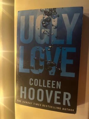 Ugly Love av Colleen Hoover - En fängslande roman med blått omslag och vattenbubblor på framsidan. Boken är skriven av Colleen Hoover och är en populär contemporary romance. Perfekt för dig som gillar känslosamma och intensiva berättelser.