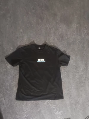 Svart Miami Beach t-shirt - Svart t-shirt från Ebon med tryck i vitt och ljusblått på bröstet där det står 'Miami Beach Florida'. Klassisk passform med rund hals och korta ärmar. Perfekt för en avslappnad och cool stil.