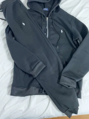 Svarta mjukisbyxor från Polo Ralph Lauren - Säljer ett par svarta mjukisbyxor från Polo Ralph Lauren med den klassiska vita loggan broderad på benet. Byxorna har dragsko i midjan och muddar vid bensluten. Perfekta för chill dagar eller när du vill vara extra bekväm.