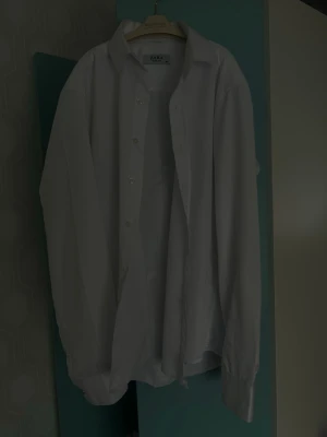Vit skjorta från Zara - Klassisk vit skjorta från Zara med lång ärm och knappar framtill. Skjortan har en tidlös design och är tillverkad i ett lätt bomullstyg som passar perfekt till många olika stilar.