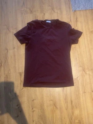Mörkbrun t-shirt från Filippa K - En stilren mörkbrun t-shirt från Filippa K med klassisk rund hals och korta ärmar. Tillverkad i mjuk bomull som känns skön mot huden. Perfekt basplagg för en enkel och clean look. Fläckarna på andra bilden är bara på kameran 