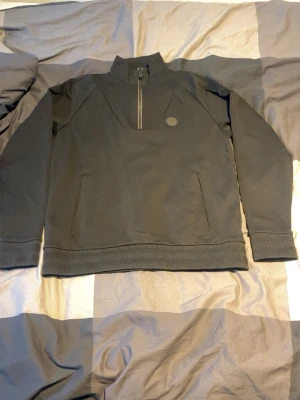 Svart half-zip hoodie från boss - Säljer en svart hoodie från Stone Island med half-zip framtill och hög krage. Hoodien har en diskret logopatch på bröstet och två snedställda fickor. Tillverkad i mjukt bomullsmaterial och har ribbade muddar vid ärmslut och nederkant.