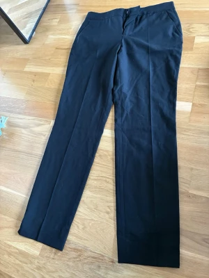  Zara Svarta raka kostymbyxor - Snygga svarta kostymbyxor med rak passform och pressveck. Byxorna har diskreta sidfickor och stängs med knapp och dragkedja. Perfekta för en stilren look och passar till många olika outfits.