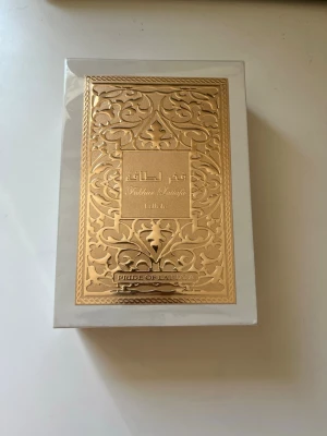 Pride of Lattafa Parfym - Helt ny och Exklusiv parfym från Lattafa i elegant vit och guld förpackning med detaljerat orientaliskt mönster. Lådan har en lyxig känsla med guldfärgad metallplatta och arabiska inskriptioner. Perfekt för dig som gillar unika dofter och snygg design. Hör av er vid minsta lilla fråga och priset kan diskuteras vid snabb affär. 