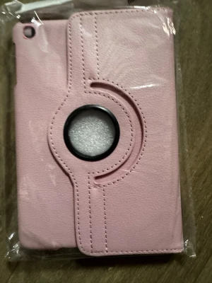 Rosa roterbart mobilskal - Snyggt rosa mobilskal med roterbar funktion och cirkelformat fönster på baksidan. Skalet är tillverkat i konstläder och har stilrena sömmar som ger ett modernt intryck. Perfekt för dig som vill ha ett praktiskt och trendigt skydd till mobilen.