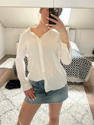Vit klassisk skjorta med knappar - Snygg vit skjorta med klassisk krage och knäppning framtill. Skjortan har lång ärm och en rak passform som ger en clean och tidlös look. Perfekt att styla till jeans eller kjol för en enkel och fräsch outfit.
