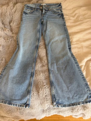 Ljusblå bootcut jeans med kedjedetalj - Säljer ett par ljusblå bootcut jeans med snygg kedjedetalj vid fickan. Jeansen har klassisk femficksdesign, låg midja och vida ben. Perfekta för dig som gillar lågmidja och lite mer baggy byxor, sitter skit snyggt men passar tyvärr inte mig längre .Materialet är denim i bomull.🩵