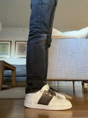 Valentino opens  - Snygga vita valentino sneakers med bred svart läderdetalj över mitten och vita snören. Skorna har en klassisk låg profil, perfekt för en stilren look perfekta nu till sommaren. Materialet är läder och designen är enkel men modern.       ‼️OBS box och dustbag ingår inte‼️ kvitto går att få. Bara att höra av dig vid funderingar